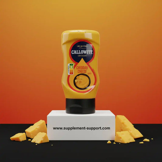 Callowfit Cheddar Cheese Sauce Flasche mit Käsewürfeln, auf Podest vor orangem Hintergrund