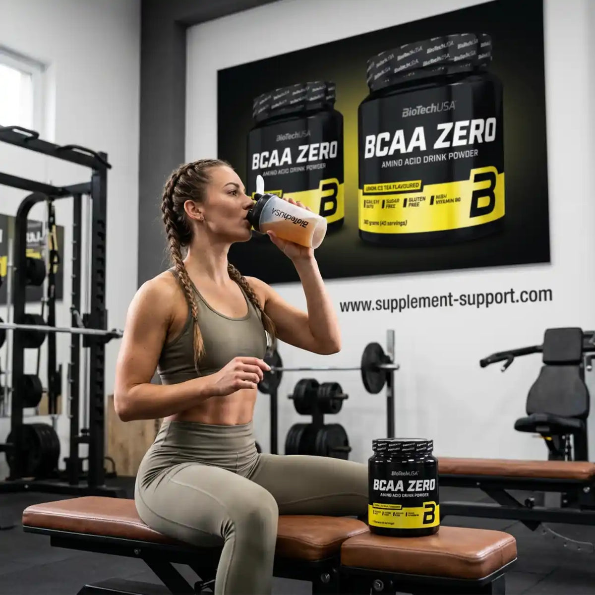 Frau im Fitnessstudio trinkt BioTech USA BCAA ZERO Aminosäure Pulver aus einem Shaker.