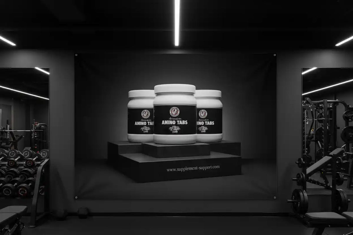 Drei weiße Dosen Amino Tabs Sportnahrung vor einem schwarzen Hintergrund im Fitnessstudio.