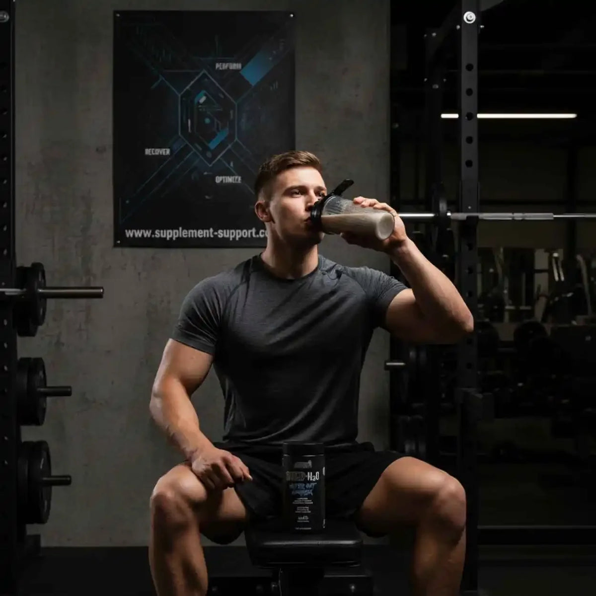 Muskulöser Mann trinkt aus einem Shaker im Fitnessstudio mit Applied Nutrition Produkt.