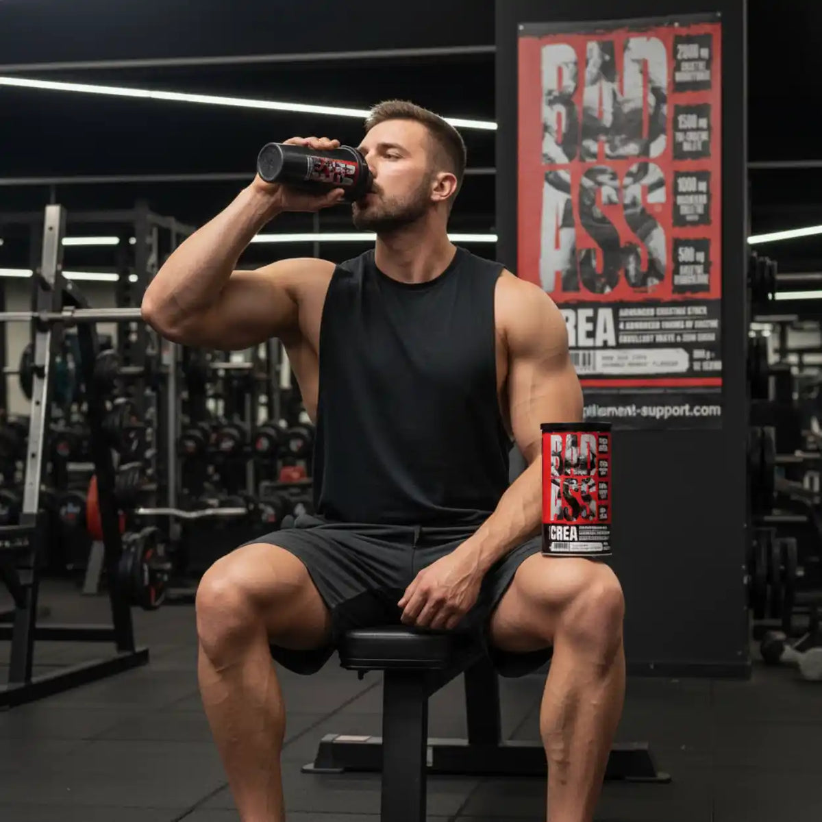 Muskulöser Mann trinkt BAD ASS CREA im Fitnessstudio, neben Dose auf Trainingsbank.