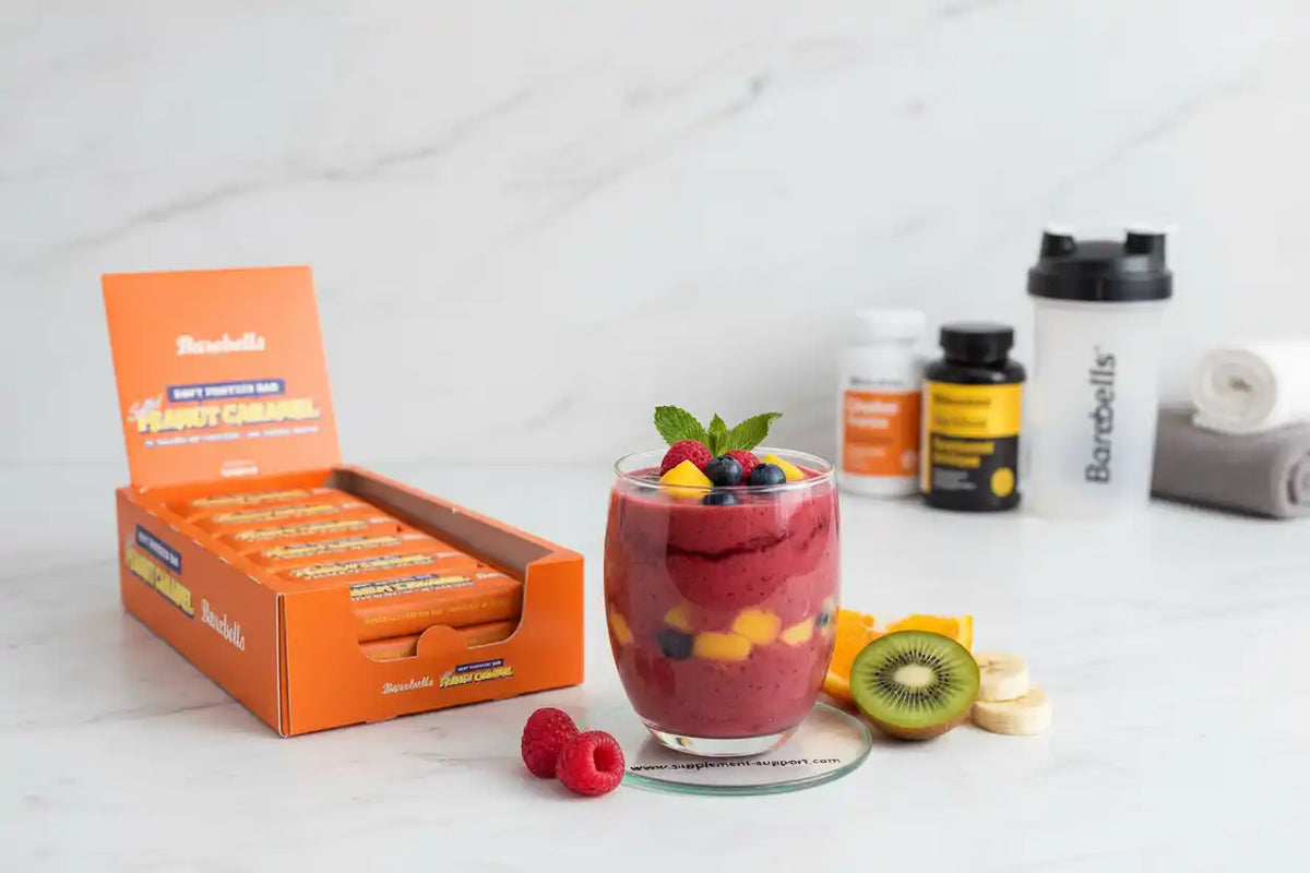 Barebells Proteinriegel Erdnuss-Karamell mit Beeren-Smoothie und Früchten für Sportler