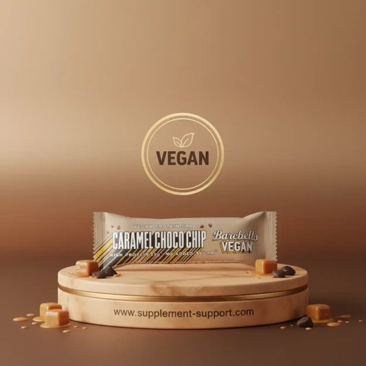 Barebells Vegan Protein Bar Caramel Choco Chip auf einem Podest mit Karamellstücken
