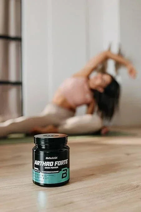 Arthro Forte Drink Powder für Sportler, im Vordergrund auf Holzboden, im Hintergrund Person beim Dehnen