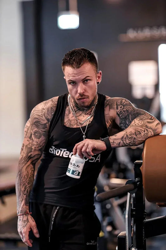 Tätowierter Athlet mit Nahrungsergänzungsmittel im Fitnessstudio, ideal für Sportler und Fitnessbegeisterte
