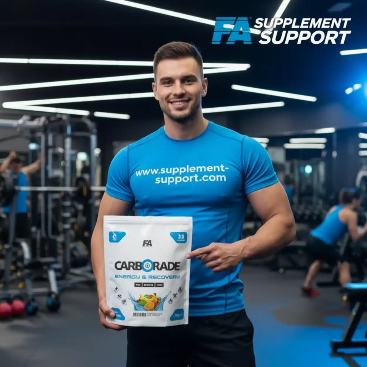 Muskulöser Mann im Fitnessstudio hält eine Packung FA Nutrition CARBORADE Kohlenhydrat Pulver.