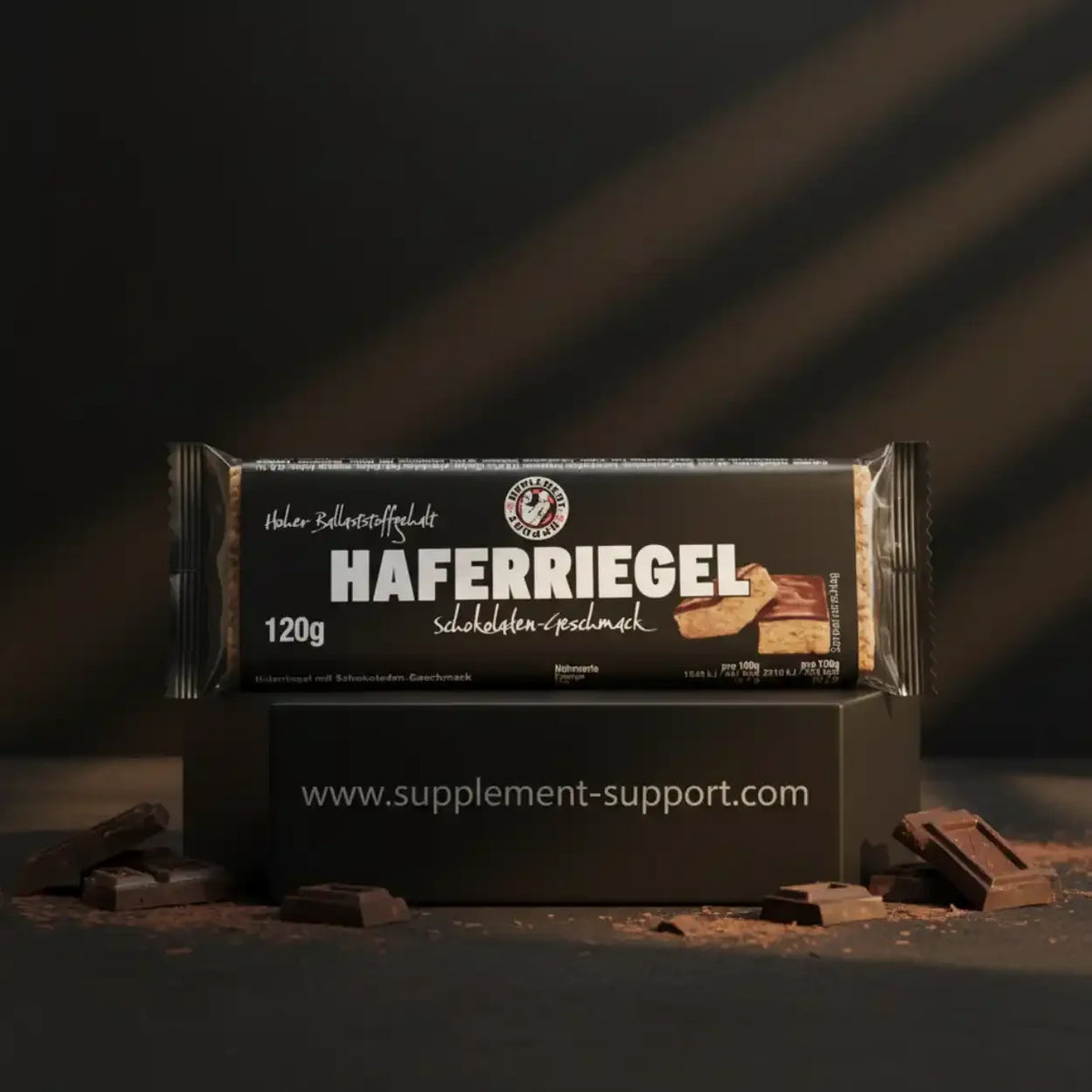 Schokoladiger Haferriegel von Supplement Support auf schwarzem Hintergrund mit Schokoladenstücken.