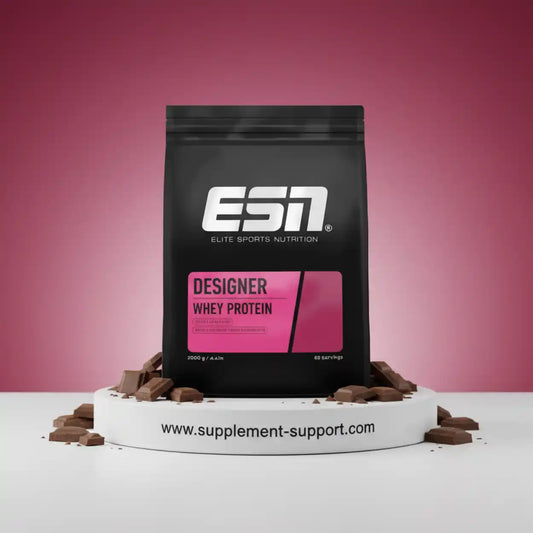 ESN Designer Whey Protein Schoko Pulver im schwarzen Beutel vor rosa Hintergrund, umgeben von Schokostücken.