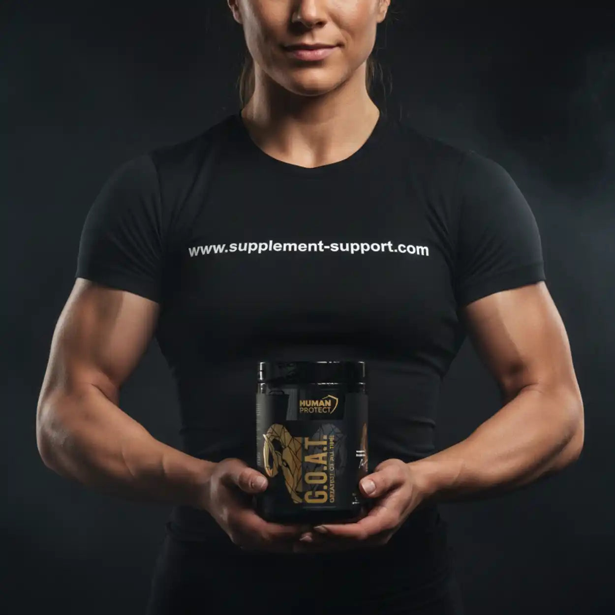 Muskulöse Sportlerin hält eine Dose G.O.A.T. Nahrungsergänzung vor dunklem Hintergrund.