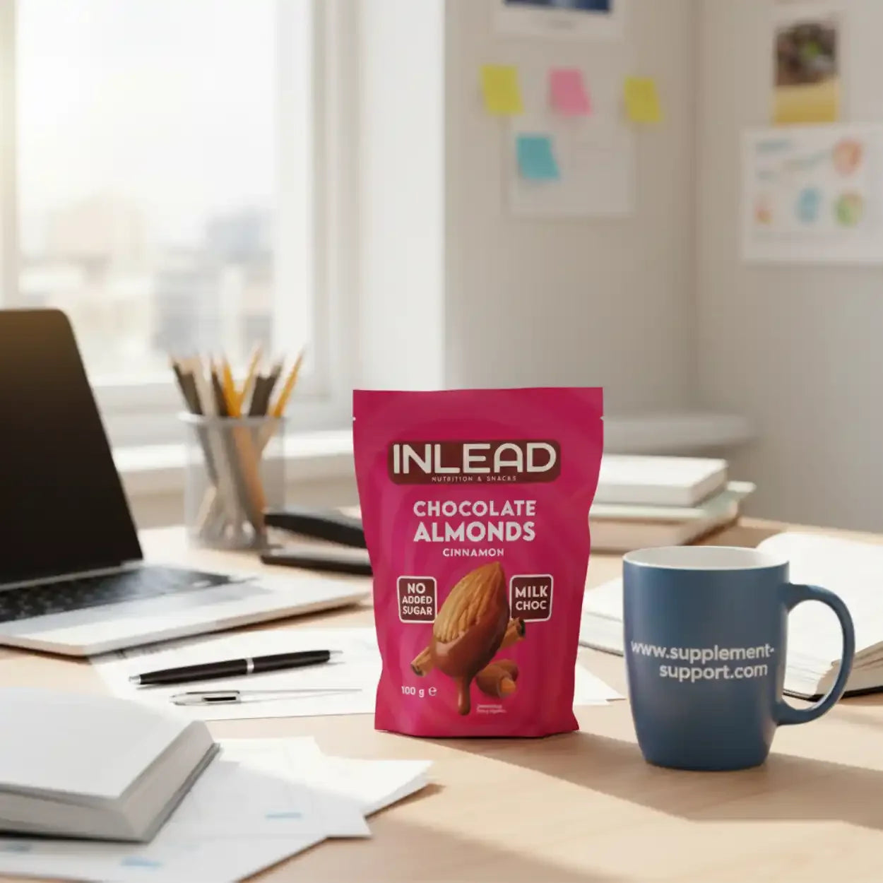 INLEAD Chocolate Almonds Zimt 100g auf Schreibtisch neben Tasse mit supplement-support.com Logo
