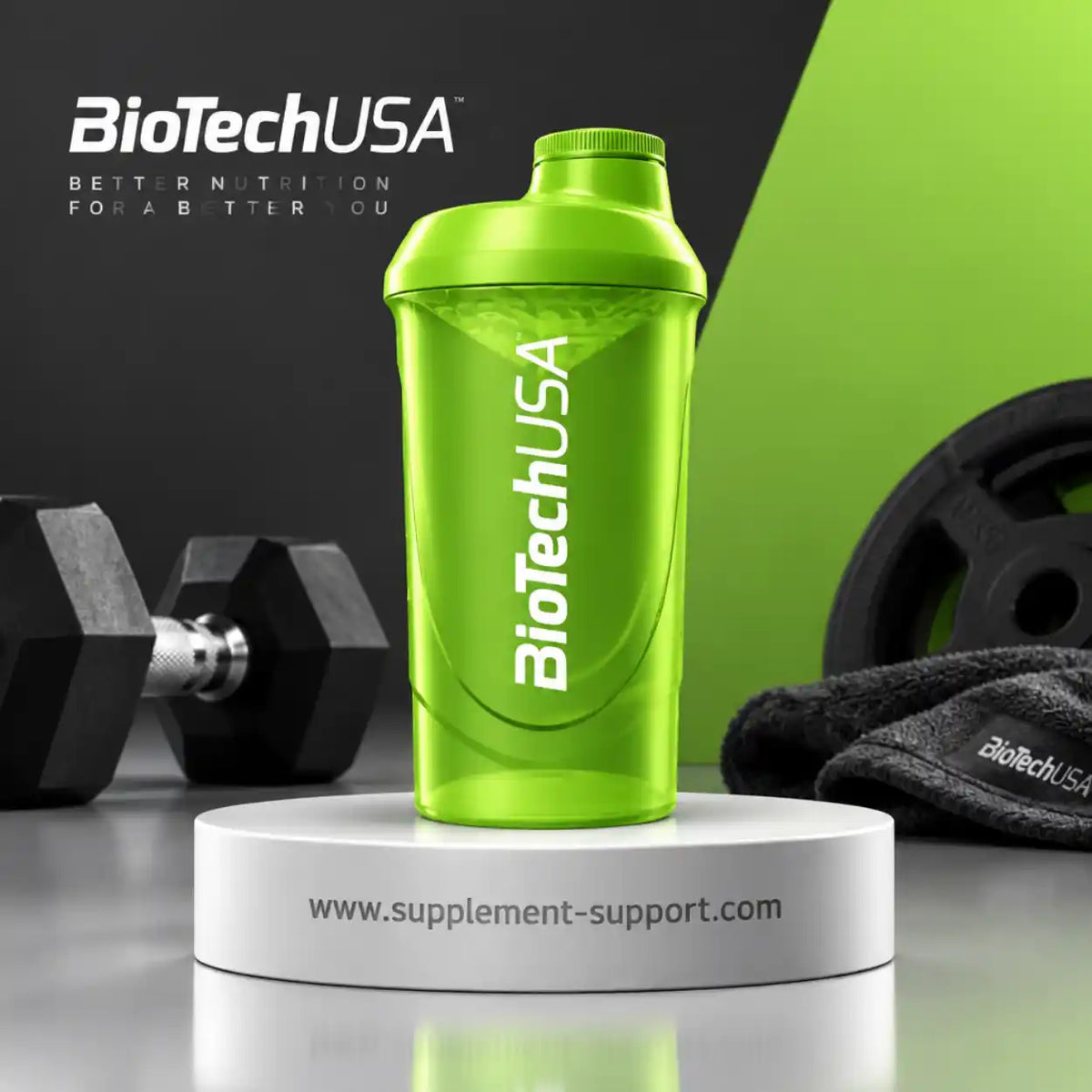 Grüner BioTech USA Protein Shaker 600ml auf einem weißen Podest mit Hanteln im Hintergrund.