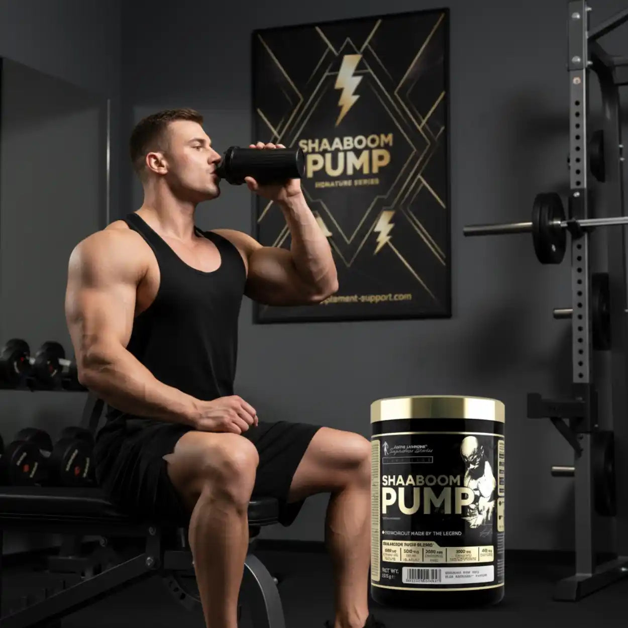Muskulöser Mann trinkt Pre-Workout Booster Shaaboom Pump im Fitnessstudio, Hantelbank im Hintergrund.