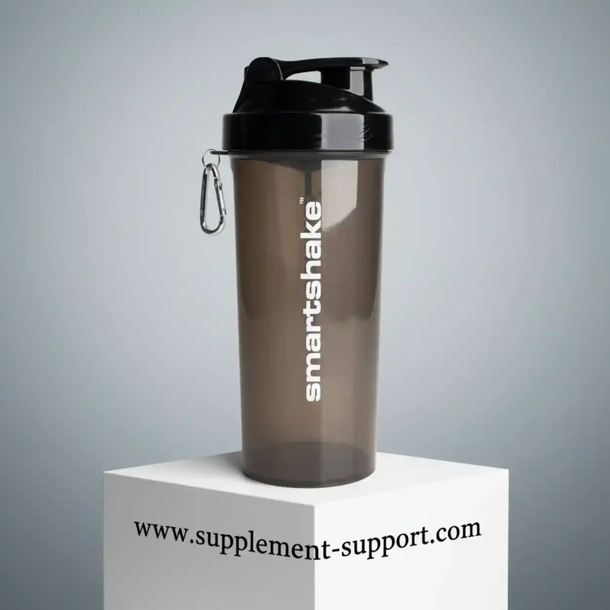 Brauner Smartshake Protein Shaker mit schwarzem Deckel auf weißem Podest