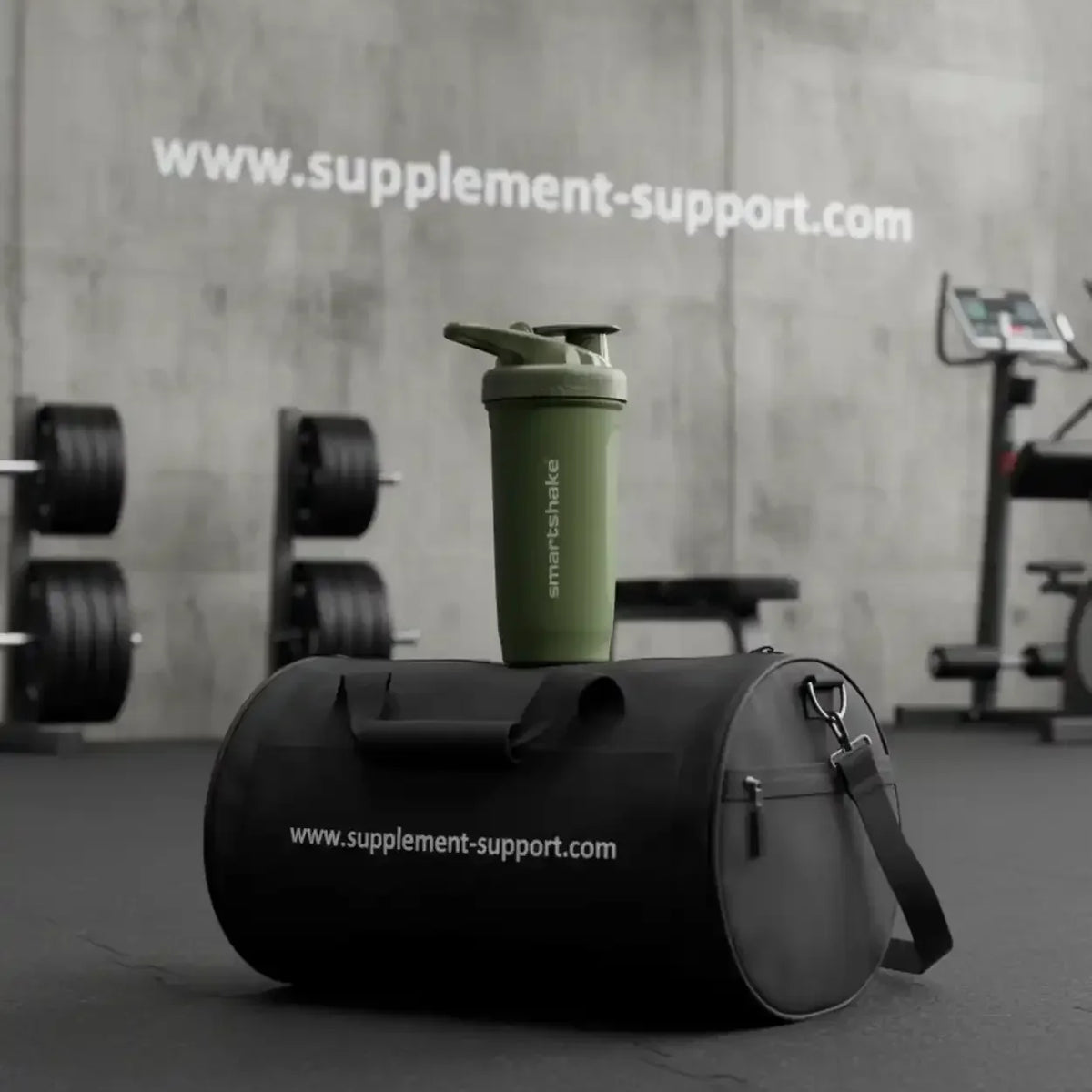 Grüner Smartshake Mixerbecher auf einer schwarzen Sporttasche im Fitnessstudio
