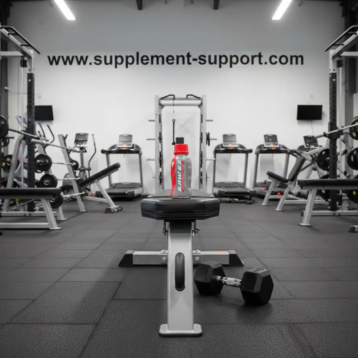 Trec SAW 2.0 Booster Shot auf Hantelbank im Fitnessstudio mit Hanteln und Trainingsgeräten
